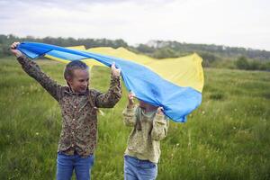 deux peu les filles dans le champ en dessous de le ukrainien drapeau dans pluie photo