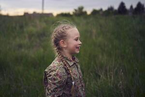 une portrait de une peu blond fille dans une champ photo