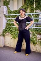 une moyen Taille femme dans une noir corset et large jambe pantalon des promenades par le ville dans le Matin lumière photo