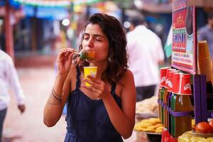 séduisant femme en mangeant la glace vas-y dans jetable tasse photo