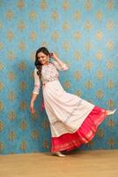 une magnifique femme dans une traditionnel robe est souriant et posant avec un jambe en haut photo