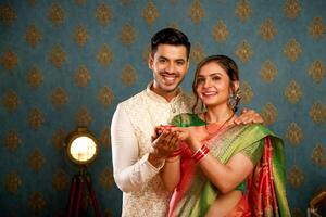 image de une content couple dans traditionnel Indien tenue à le diwali festival, tous les deux en portant une diya photo