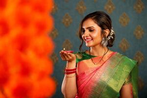 une charmant Jeune femme dans traditionnel Indien Vêtements en portant une diya tandis que sourire à le Festival de diwali photo