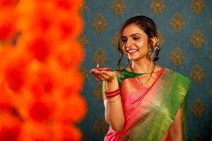 souriant magnifique femme au foyer dans sari en portant diya pendant diwali Festival photo