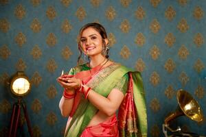 un innocent Jeune femme dans sari en portant diya pendant diwali Festival photo