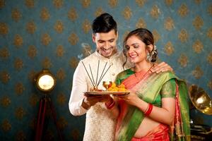 image de une charmant couple en portant pooja assiette pour le Festival de diwali photo