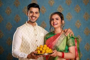 souriant magnifique couple dans traditionnel Indien tenue en portant assiette de ladoo photo