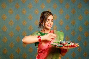 une beau femme dans traditionnel Indien tenue détient une assiette de diyas pendant le fête de diwali photo