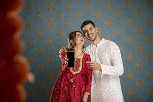 image de un adorable couple portant traditionnel Indien tenue en portant une assiette de ladoos dans leur mains et sourire photo