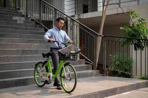 une concentré asiatique homme d'affaire pousser une vert vélo dans le ville, Aller à travail avec le sien vélo. photo