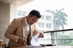 une déterminé asiatique homme d'affaire recherche pour une document, concentrer sur une document sur une tableau. photo