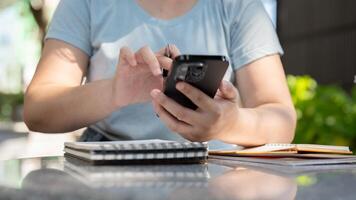 une femme séance à un Extérieur tableau, en train de lire information sur sa téléphone tandis que travail à distance. photo
