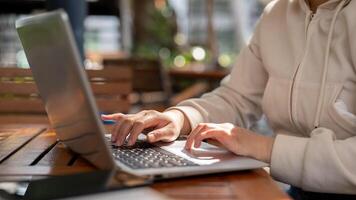 une femme travail à distance à une café, en ligne sur sa portable ordinateur, et dactylographie sur le clavier. photo