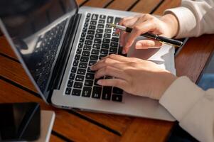 une femme répondre à courriels sur sa portable ordinateur, dactylographie sur le clavier, et travail en ligne. photo