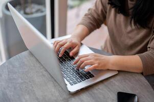 une femme travail sur sa portable ordinateur dans une café, dactylographie sur le portable clavier, répondre à email photo