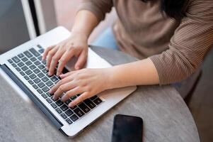 une femme travail sur sa portable ordinateur dans une café, dactylographie sur le portable clavier, répondre à email photo