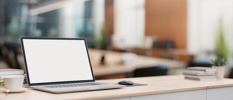 une portable ordinateur sur une minimal bois table avec une flou Contexte de une moderne réunion chambre. photo