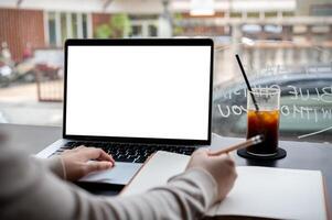 une fermer image de une Université étudiant en train d'étudier en ligne sur sa portable ordinateur à une café magasin. photo