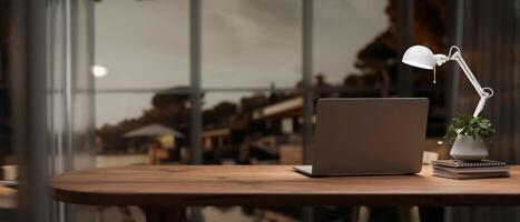 une portable ordinateur sur une en bois table près le fenêtre dans une contemporain Accueil Bureau ou privé bureau. photo