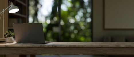 une contemporain, confortable Accueil Bureau espace de travail Caractéristiques une portable ordinateur sur une table dans le chambre. photo