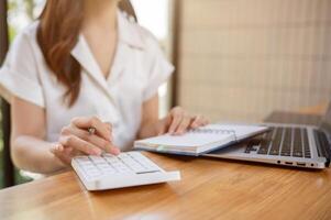 une tondu image de une femme d'affaires en utilisant une calculatrice, travail dans le bureau. photo