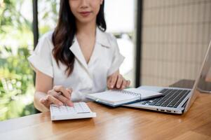 une tondu image de une femme d'affaires en utilisant une calculatrice, travail dans le bureau. photo