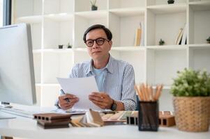 une professionnel Sénior asiatique Masculin intérieur designer ou architecte travail dans le sien moderne bureau. photo