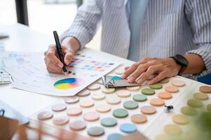 un intérieur designer travail sur une projet dans le bureau, vérification Couleur échantillons sur une échantillon palette. photo