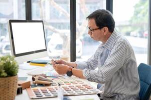 un expérimenté asiatique Masculin intérieur designer ou architecte est travail sur le sien projet dans le bureau. photo