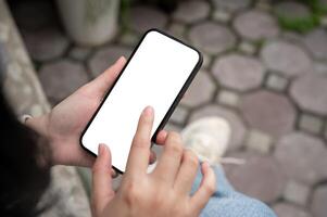 une fermer image de une femme en utilisant sa téléphone intelligent tandis que séance en plein air. photo