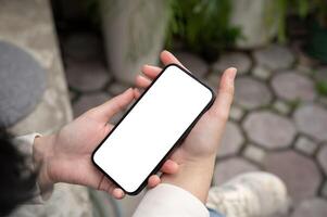 une fermer image de une femme en train de lire ou en train de regarder vidéos sur sa téléphone intelligent tandis que séance en plein air. photo