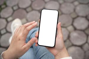 une fermer image de une femme en utilisant sa téléphone intelligent tandis que séance en plein air. photo