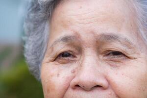 fermer de visage personnes âgées femme souriant bonheur, court blanc cheveux, et à la recherche à le caméra. asiatique Sénior femme en bonne santé et avoir positif pensées sur la vie faire sa content chaque journée photo