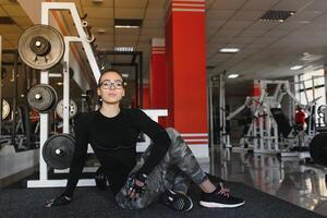 jolie fille Faire élongation des exercices sur le sol à le salle de sport. photo