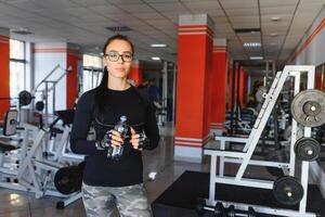 Jeune femme en buvant l'eau après faire de l'exercice. aptitude salle de sport. photo