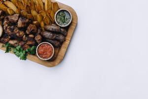 plus Viande plat - du boeuf brochettes, saucisses, grillé champignons, patates, tomates et sauce. le meilleur choix pour une bière. fermer sur une blanc Contexte photo