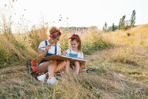 Jeune mère et sa fille avoir amusant, de la mère journée. souriant mère avec magnifique fille dessine la nature. photo