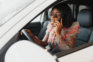 magnifique Jeune mixte course noir africain américain femme conduite voiture et parle par téléphone photo