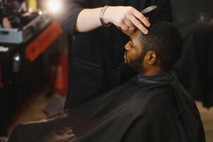 noir homme dans le salon de coiffure. mignonne noir homme fait du une la Coupe de cheveux dans le africain salon. cheveux style. la Coupe de cheveux pour adultes. photo