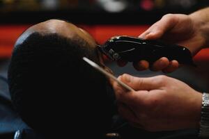 noir homme dans le salon de coiffure. mignonne noir homme fait du une la Coupe de cheveux dans le africain salon. cheveux style. la Coupe de cheveux pour adultes. photo