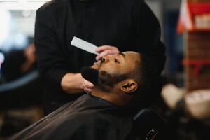 noir homme dans le salon de coiffure. mignonne noir homme fait du une la Coupe de cheveux dans le africain salon. cheveux style. la Coupe de cheveux pour adultes. photo