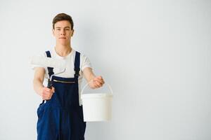 Jeune homme dans bleu salopette La peinture mur dans blanc Couleur avec une rouleau photo