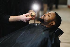 noir homme dans le salon de coiffure. mignonne noir homme fait du une la Coupe de cheveux dans le africain salon. cheveux style. la Coupe de cheveux pour adultes. photo