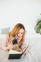 fille en train de lire une livre. mignonne fille en train de lire une livre avec sa chien à maison. jolie élégant fille. photo