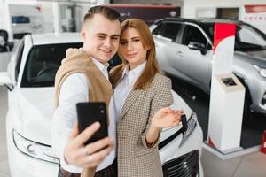 famille selfie dans concession. content Jeune couple choisit et achat une Nouveau voiture pour le famille photo