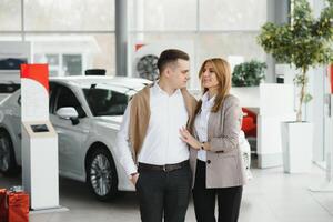 Jeune couple en utilisant une voiture dans une voiture salle d'exposition. photo