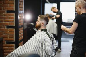 coiffeur magasin. homme dans barbier chaise, coiffeur coiffant le sien cheveux. photo