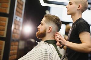 coiffeur magasin. homme dans barbier chaise, coiffeur coiffant le sien cheveux. photo