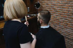 coiffeur femme Coupe homme cheveux à le salon de coiffure. femme travail comme une coiffeur. petit affaires concept photo