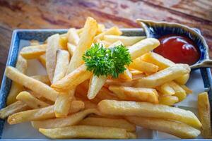 fermer de français frites et patates sauce sur une assiette sur vieux en bois tableau. casse-croûte nourriture coloré et sélectif concentrer photo